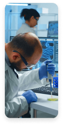 Lab technician using a pipette while monitoring data during a clinical research study